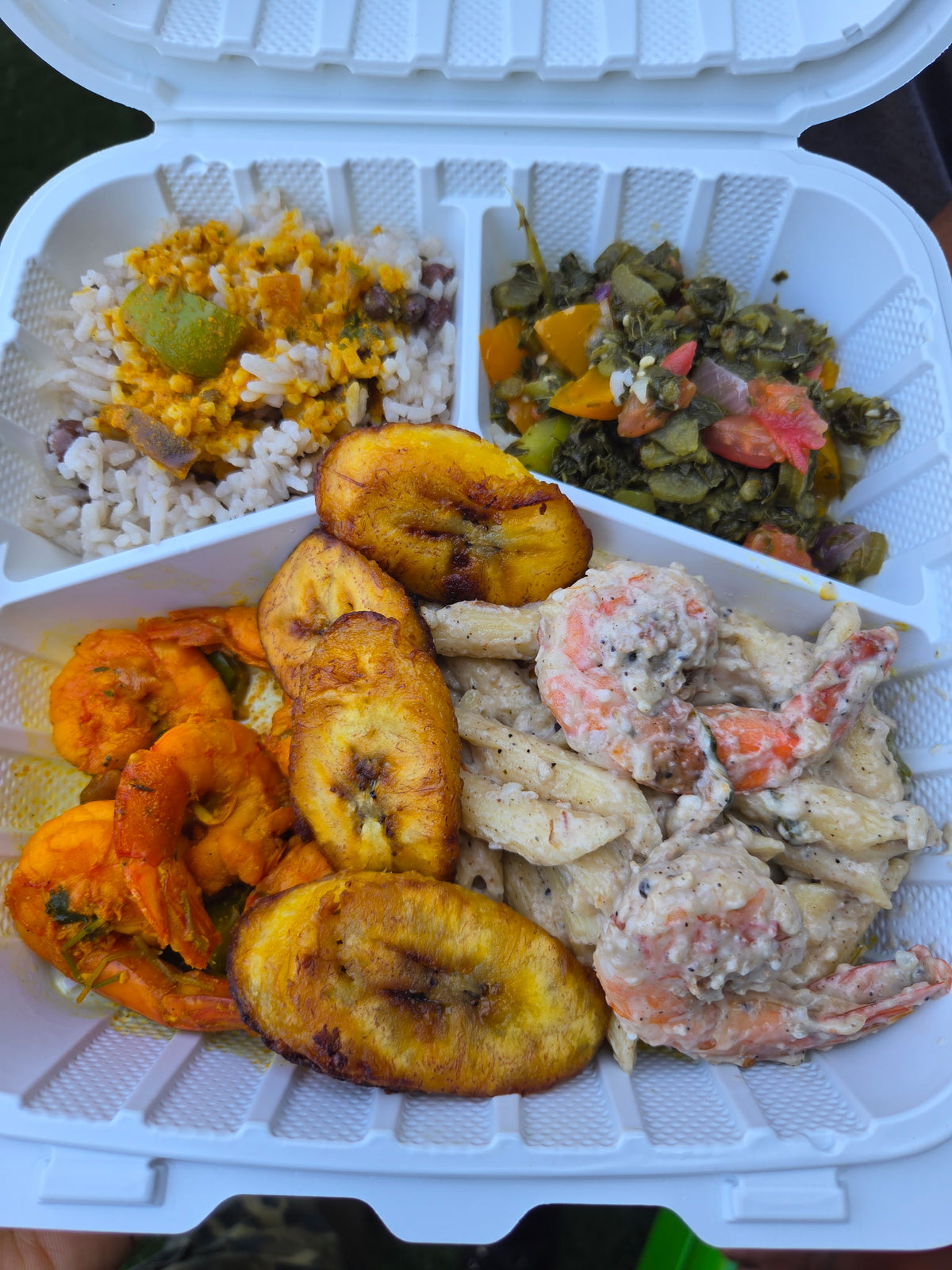 Cultural comfort food plate with stewed shrimp, rice, callaloo, fried plantains and creamy pasta salad